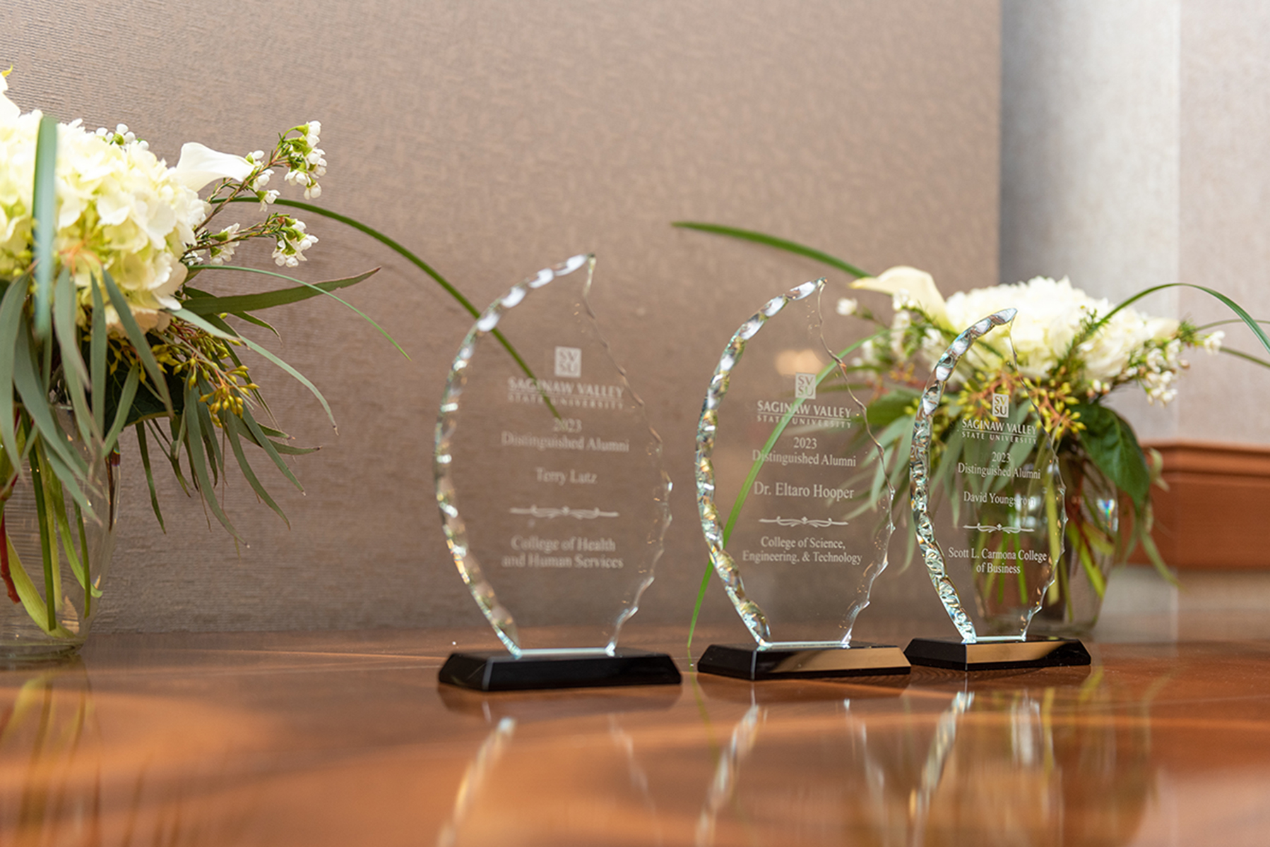 Tabletop holding three crystal awards, flowers